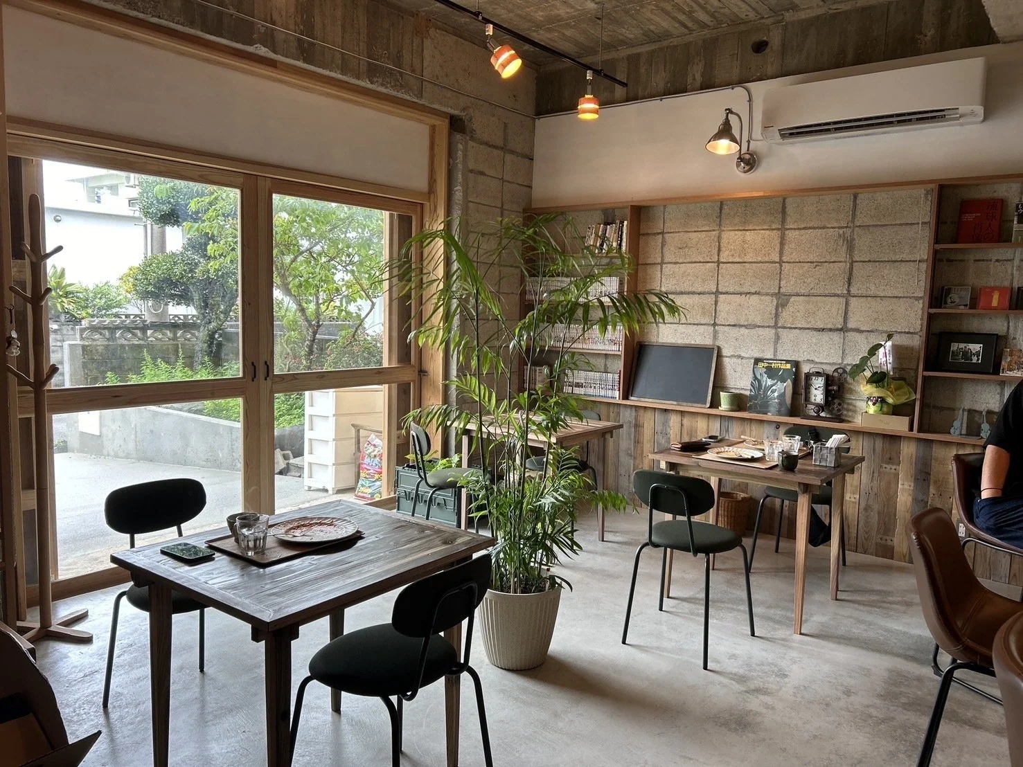 安波茶屋の客席。木の窓や造作棚、テーブルと植栽のある店内